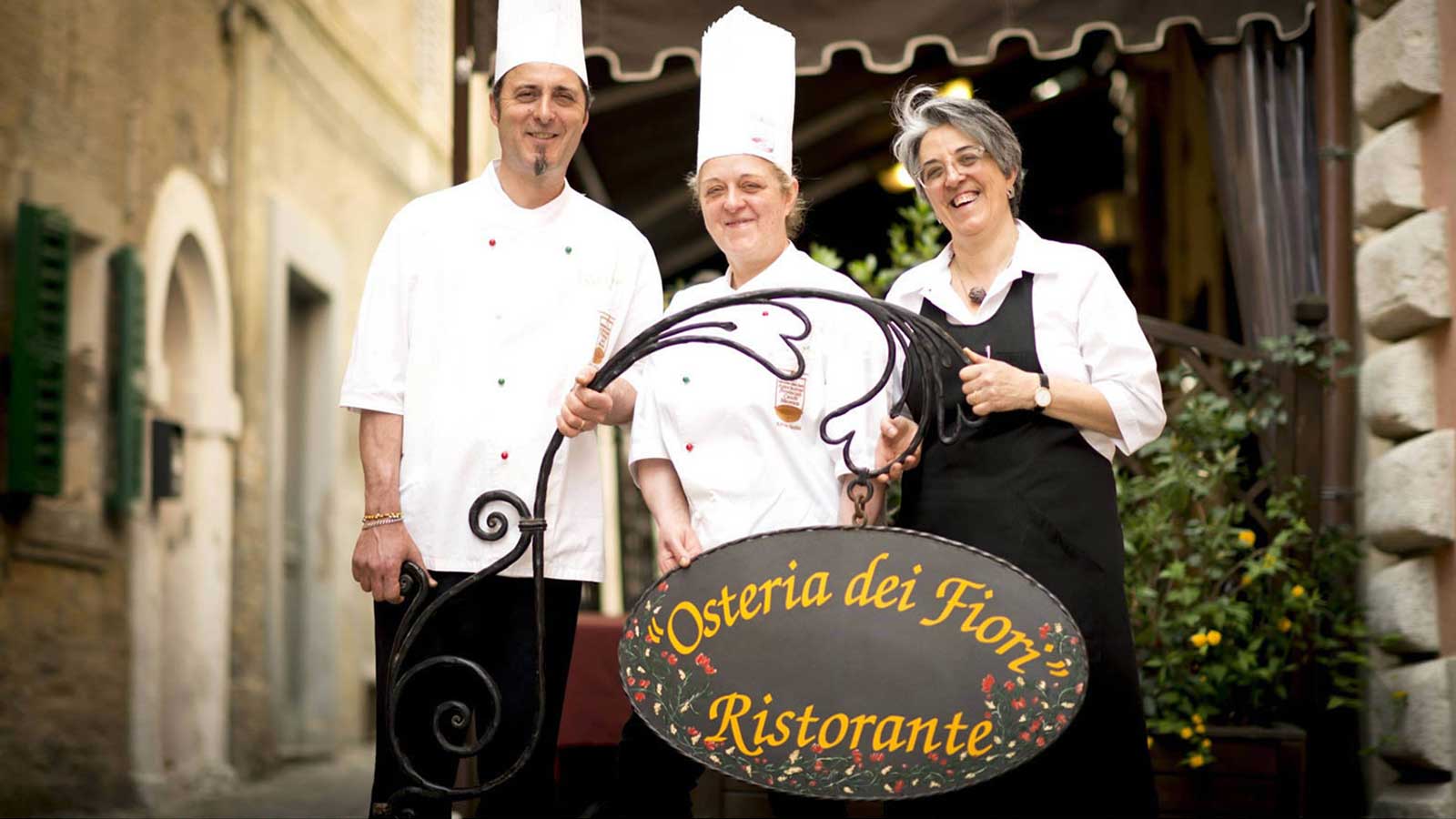 I fratelli Carducci sorridenti sorreggono l'insegna del ristorante.